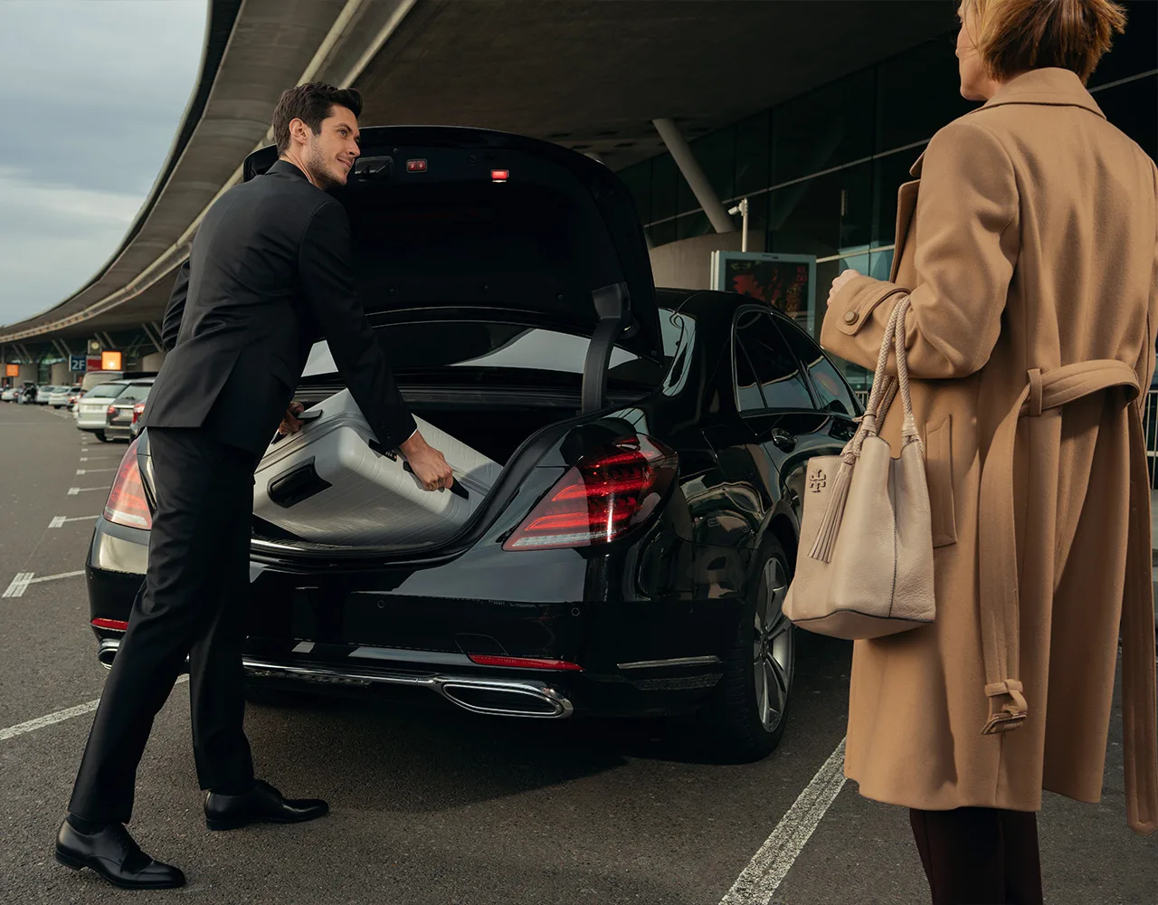 Professioneller Chauffeur öffnet die Tür eines luxuriösen Fahrzeugs für einen Kunden beim Düsseldorf-Wesel Transfer.